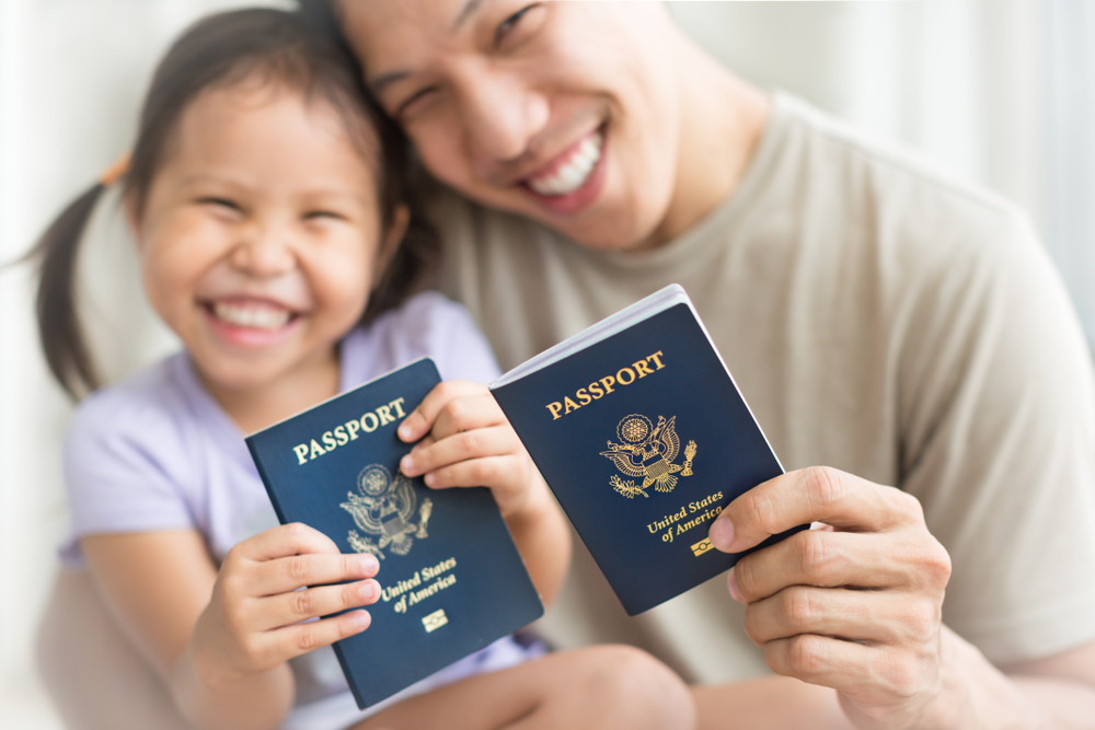 Dad and daughter holding American passports with pride. Immigration citizenship