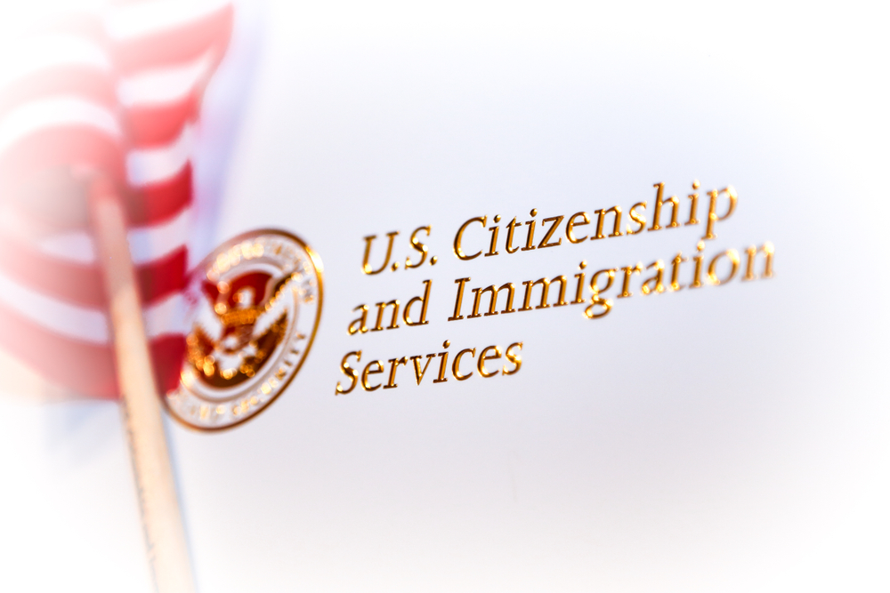 Closeup of official letter from US Citizenship and Immigration Services for becoming a citizen in the United States after going through the naturalization process. Part of American Flag in background.